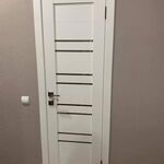 Межкомнатная белая дверь в интерьере квартиры с окрашенными стенами.